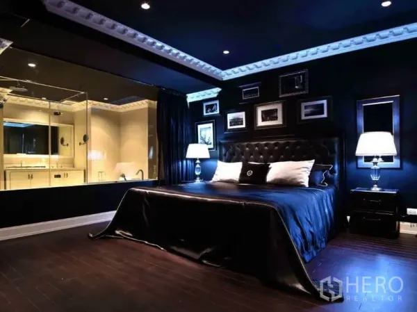 Condominium for rent or sale in Khlong Toei, Bangkok - Master bedroom with dark palette, tufted headboard and glass-walled en-suite bathroom.