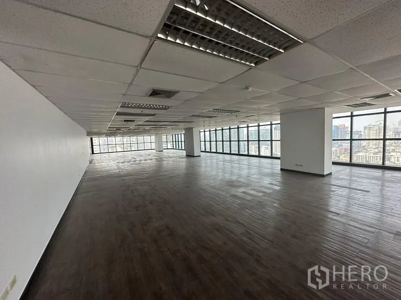 Office Space for rent - Spacious office space with wood-look floors, ceiling lights and full-height windows on two sides.