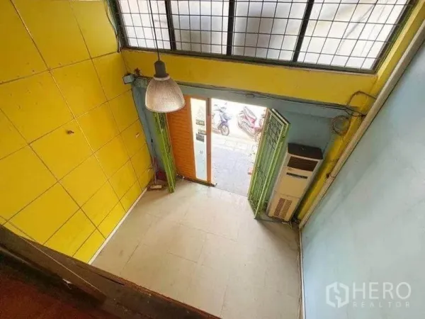 Shophouse for rent in Bang Rak, Bangkok - Double-height street-front retail space with yellow walls, tiled floor, and folding doors opening to the sidewalk.