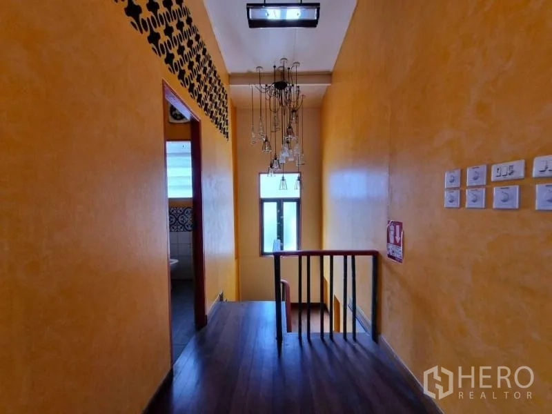 Detached House for rent in Khlong Toei, Bangkok - Stair landing with chandelier lighting and yellow textured walls.