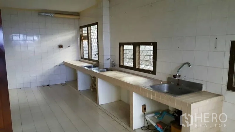 Detached House for rent in Khlong Toei, Bangkok - Large tiled kitchen with long countertops, double sinks and ventilated windows.