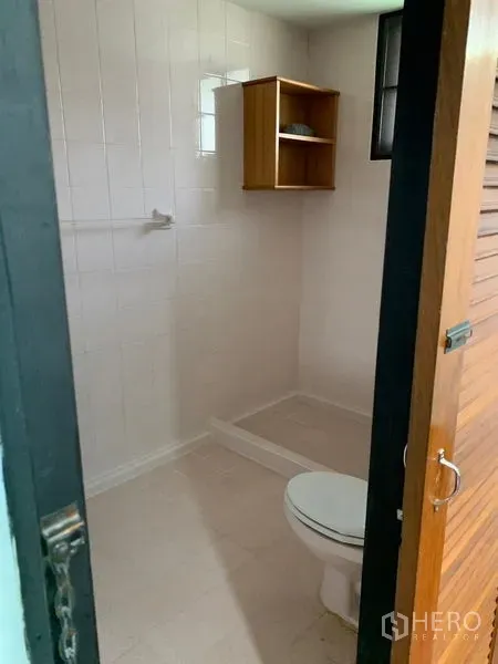 บ้าน ให้เช่าในKhlong Toei, Bangkok - ห้องน้ำปูกระเบื้องสีขาว มีโถสุขภัณฑ์ พื้นที่อาบน้ำ และชั้นไม้เล็ก
