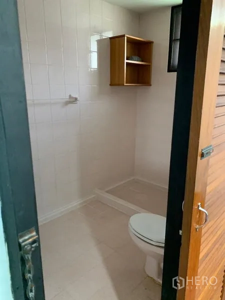 บ้าน ให้เช่าในKhlong Toei, Bangkok - ห้องน้ำปูกระเบื้องสีขาว มีโถสุขภัณฑ์ พื้นที่อาบน้ำ และชั้นไม้เล็ก