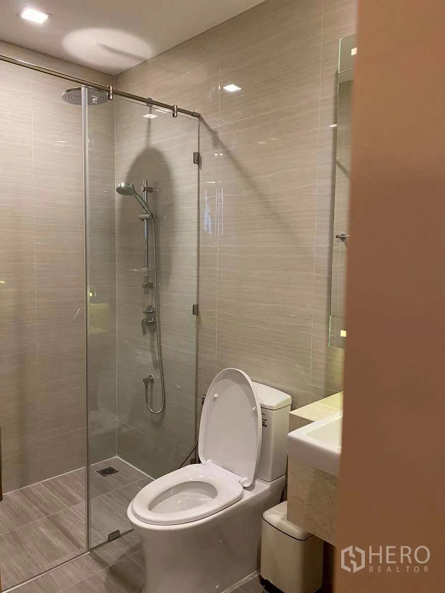 Condominium for rent in Watthana, Bangkok - Contemporary bathroom with glass-enclosed shower and toilet.
