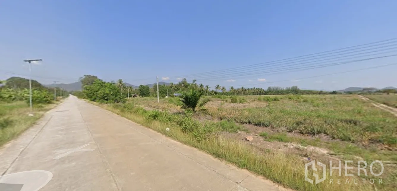 Land for sale in Mueang Prachuap Khiri Khan, Prachuap Khiri Khan - Roadside view of agricultural land and power lines toward low mountains.