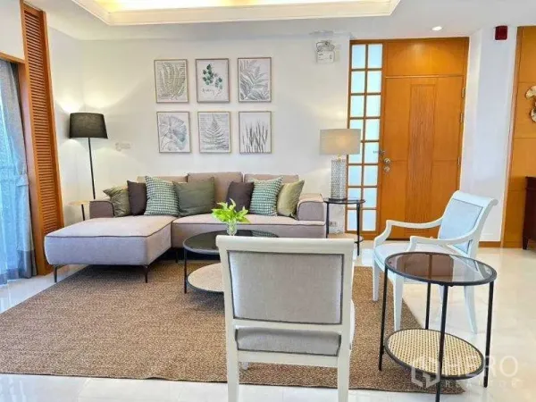 房间 出租 - 舒适客厅，转角沙发、休闲椅与植物装饰画，沙吞现代公寓内景。