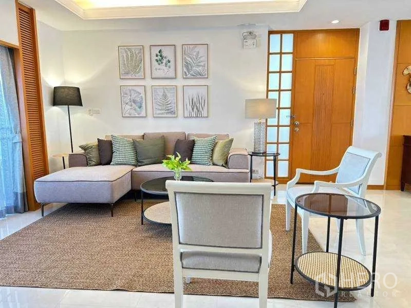 房间 出租 - 舒适客厅，转角沙发、休闲椅与植物装饰画，沙吞现代公寓内景。