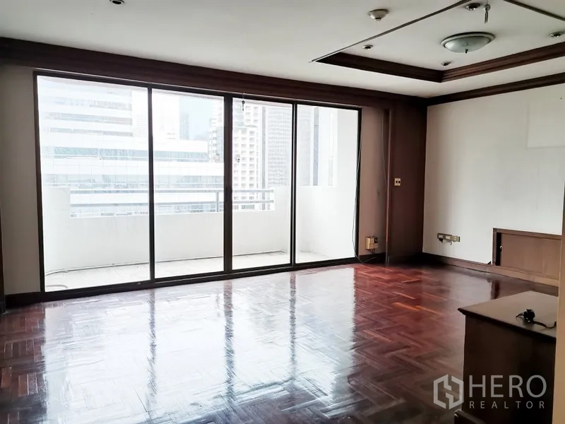 Condominium for sale in Watthana, Bangkok - Spacious living room with parquet floors and floor-to-ceiling sliding glass doors opening to a balcony in a Watthana Bangkok condo.