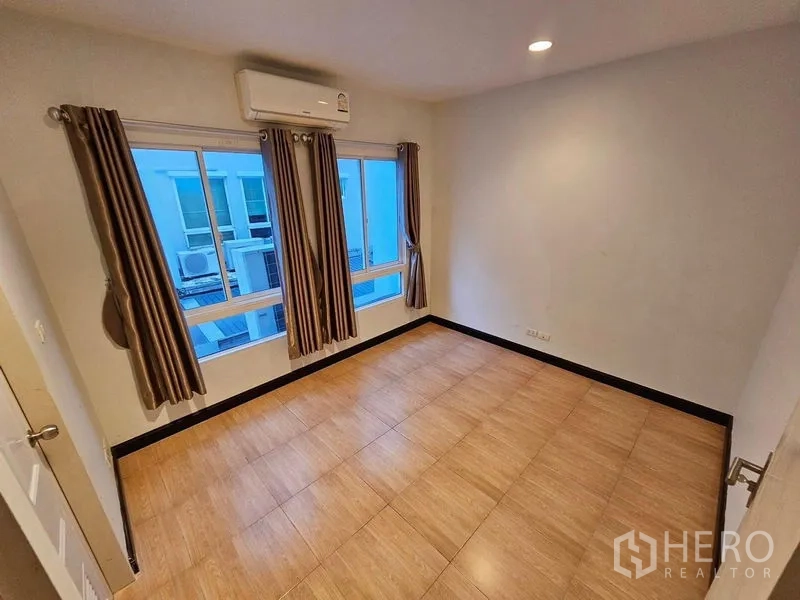 Townhouse for rent in Wang Thonglang, Bangkok - Air-conditioned bedroom with large windows, curtains, and tiled floor.