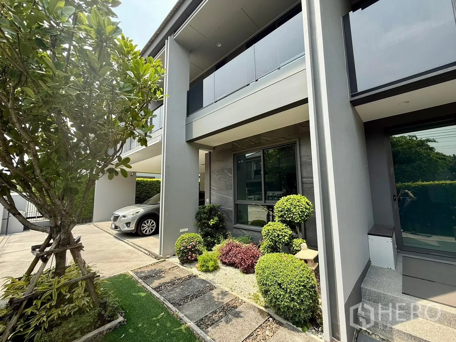Detached House for rent in Bang Kapi, Bangkok - Driveway and carport beside manicured garden and modern exterior columns.