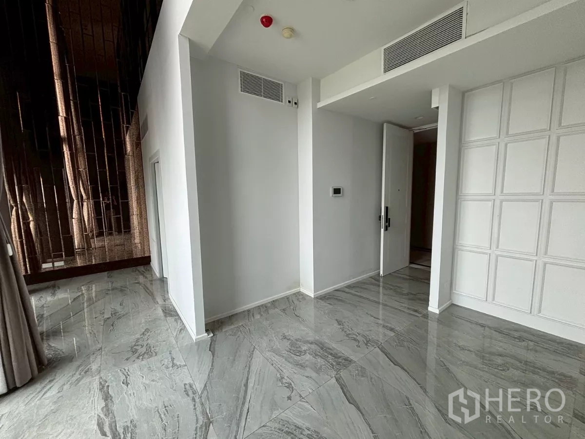 Condominium for sale in Bang Kho Laem, Bangkok - Entrance foyer with grey stone floors, wall thermostat and tall bronze accent wall near large windows.