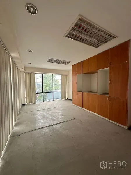 Warehouse for rent in Suan Luang, Bangkok - Office room featuring built-in wooden cabinets and full-height windows with blinds.