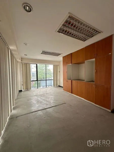 Warehouse for rent in Suan Luang, Bangkok - Office room featuring built-in wooden cabinets and full-height windows with blinds.