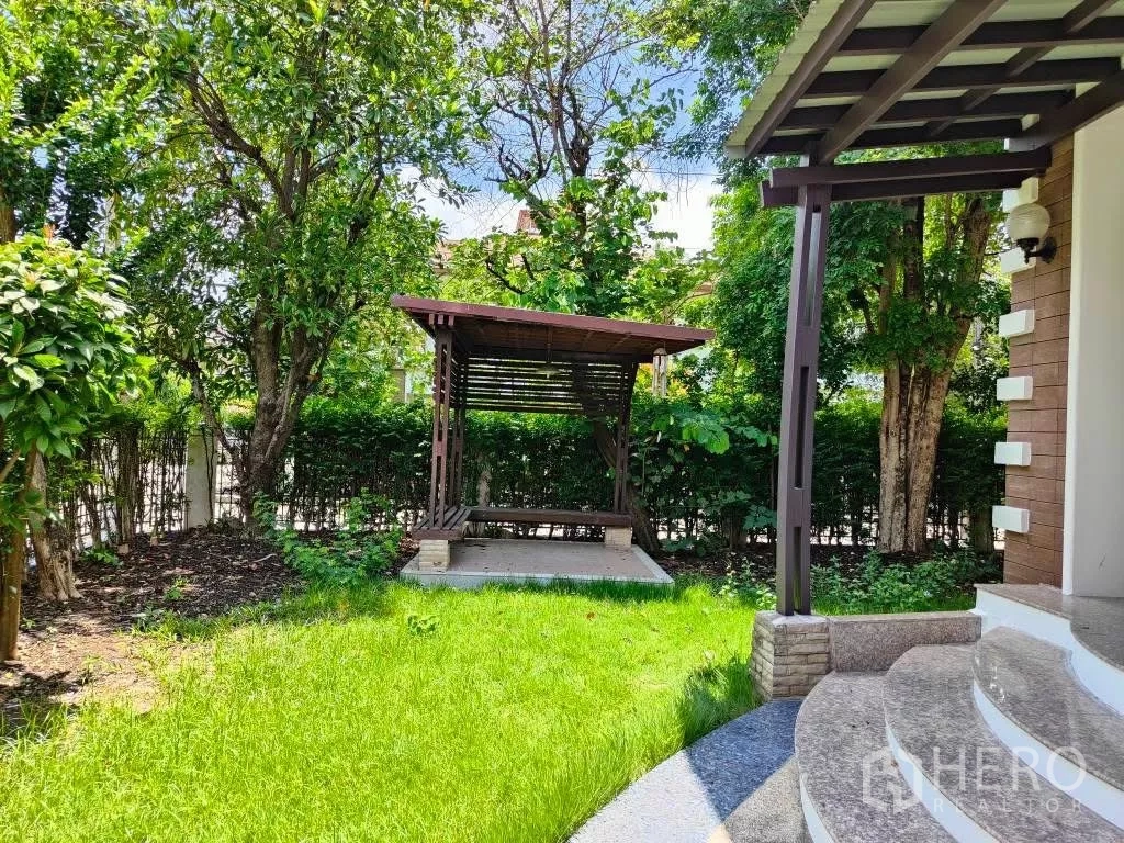 独立式住宅 出租或出售在Mueang Nonthaburi, Nonthaburi - 前院绿草如茵，设有木质凉亭，周围树木与绿篱环绕。