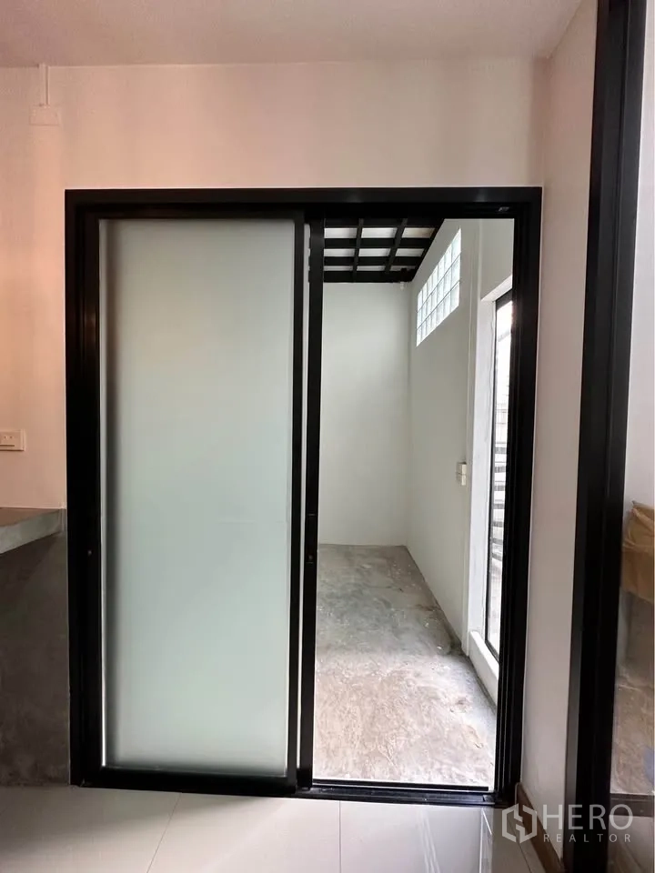 Townhouse for rent in Pak Kret, Nonthaburi - Frosted sliding door opening to compact service or storage area with glass blocks.