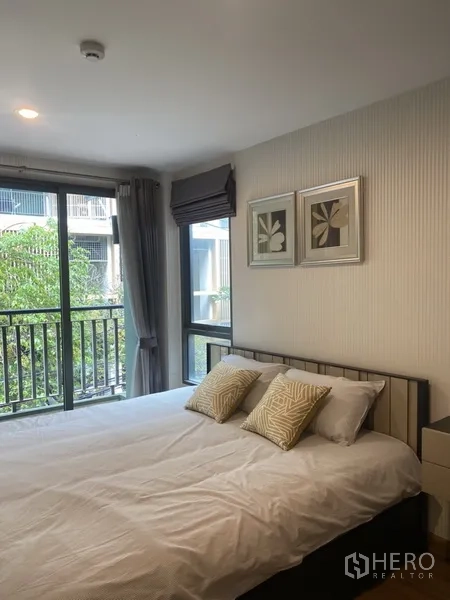 Condominium for rent in Watthana, Bangkok - Airy bedroom with large windows, balcony rail and a pleasant garden outlook.