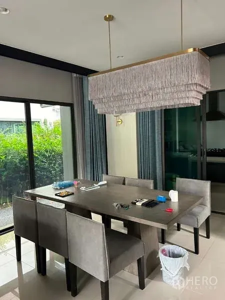 Detached House for rent in Bang Kapi, Bangkok - Dining area with six-seat table, modern layered pendant light and sliding glass doors to the garden.