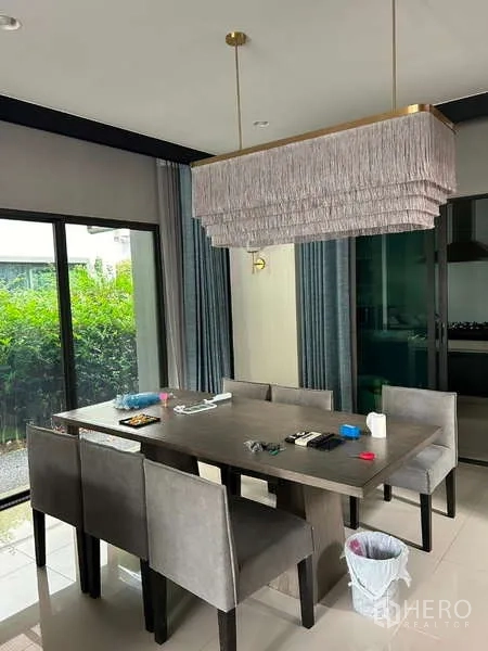 Detached House for rent in Bang Kapi, Bangkok - Dining area with six-seat table, modern layered pendant light and sliding glass doors to the garden.