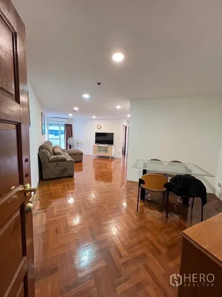 Condominium for rent in Ratchathewi, Bangkok - Entrance view into a bright living-dining area with parquet floor, sofa and TV.