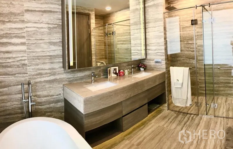 Condominium for rent in Watthana, Bangkok - Luxurious bathroom with double vanity, glass shower enclosure, and a standalone bathtub.