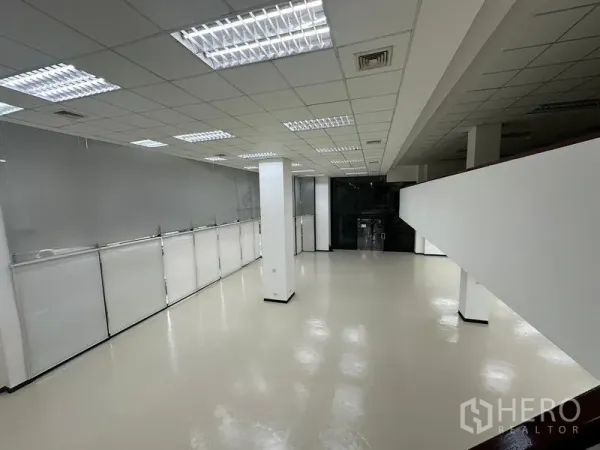 展厅 出租 - 夹层下方的开放零售空间，立柱与格栅天花灯一应俱全。