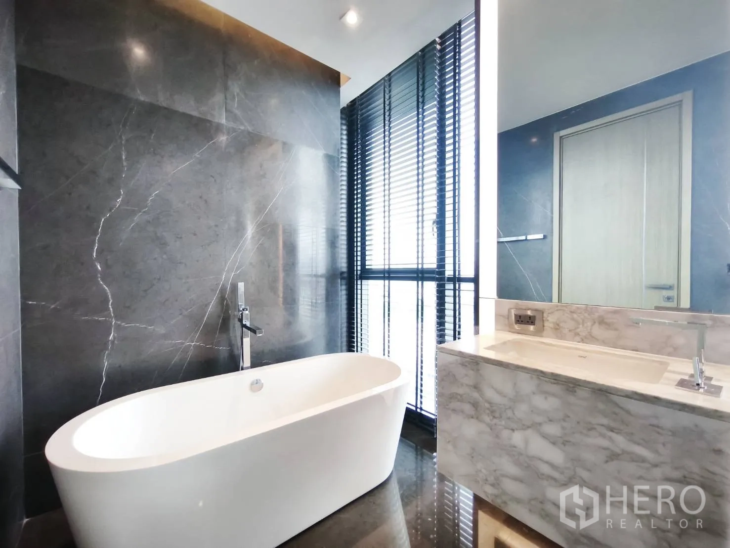 Condominium for rent in Watthana, Bangkok - Luxurious bathroom with freestanding bathtub, marble vanity, and window blinds.