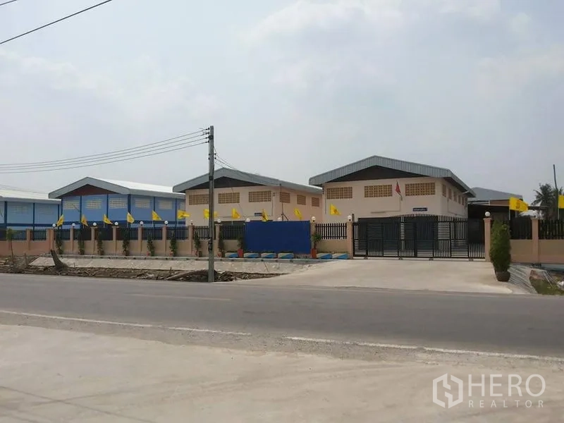 工厂 出租在Lat Lum Kaeo, Pathum Thani - 带围栏与大门的厂区外观，多个仓库建筑与宽阔混凝土出入口临路而建