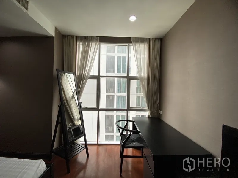 คอนโด ให้เช่าในWatthana, Bangkok - มุมทำงานในห้องนอน หน้าต่างบานใหญ่ โต๊ะยาวสีดำ เก้าอี้ และกระจกยืน