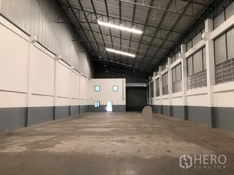 Factory for rent or sale in Bang Phli, Samut Prakan - Warehouse hall facing a loading shutter with an internal office block at the far end.