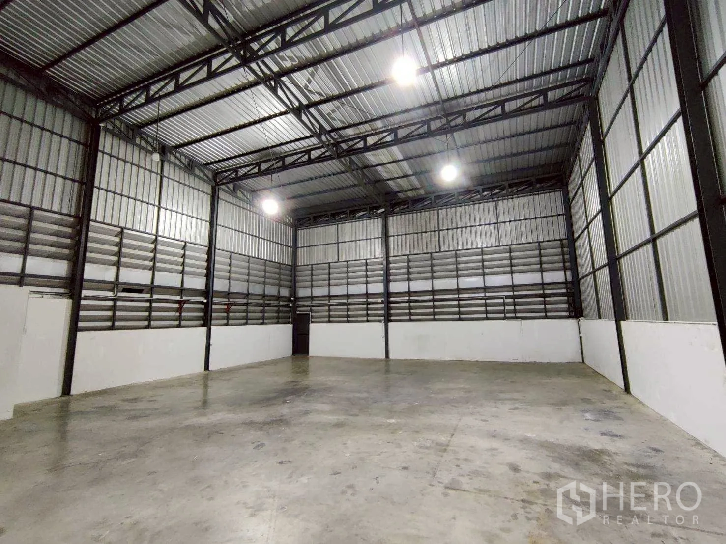 Warehouse for rent in Lam Luk Ka, Pathum Thani - Clear-span interior showing ventilation louvers and side service door.