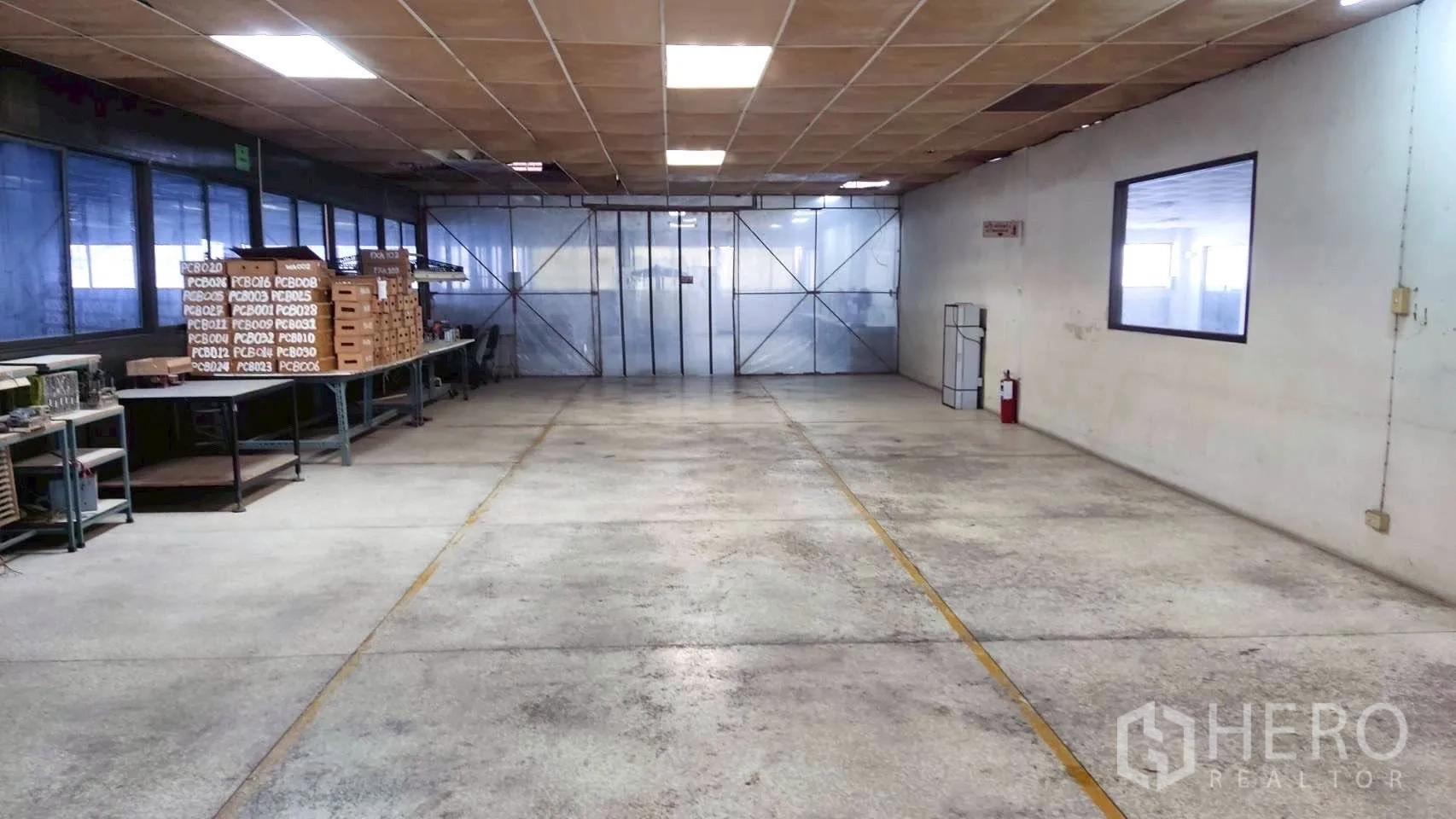 工厂 for sale in Lat Krabang, Bangkok - 车间区域设工作台与货架，荧光灯照明，金属滑门分隔。
