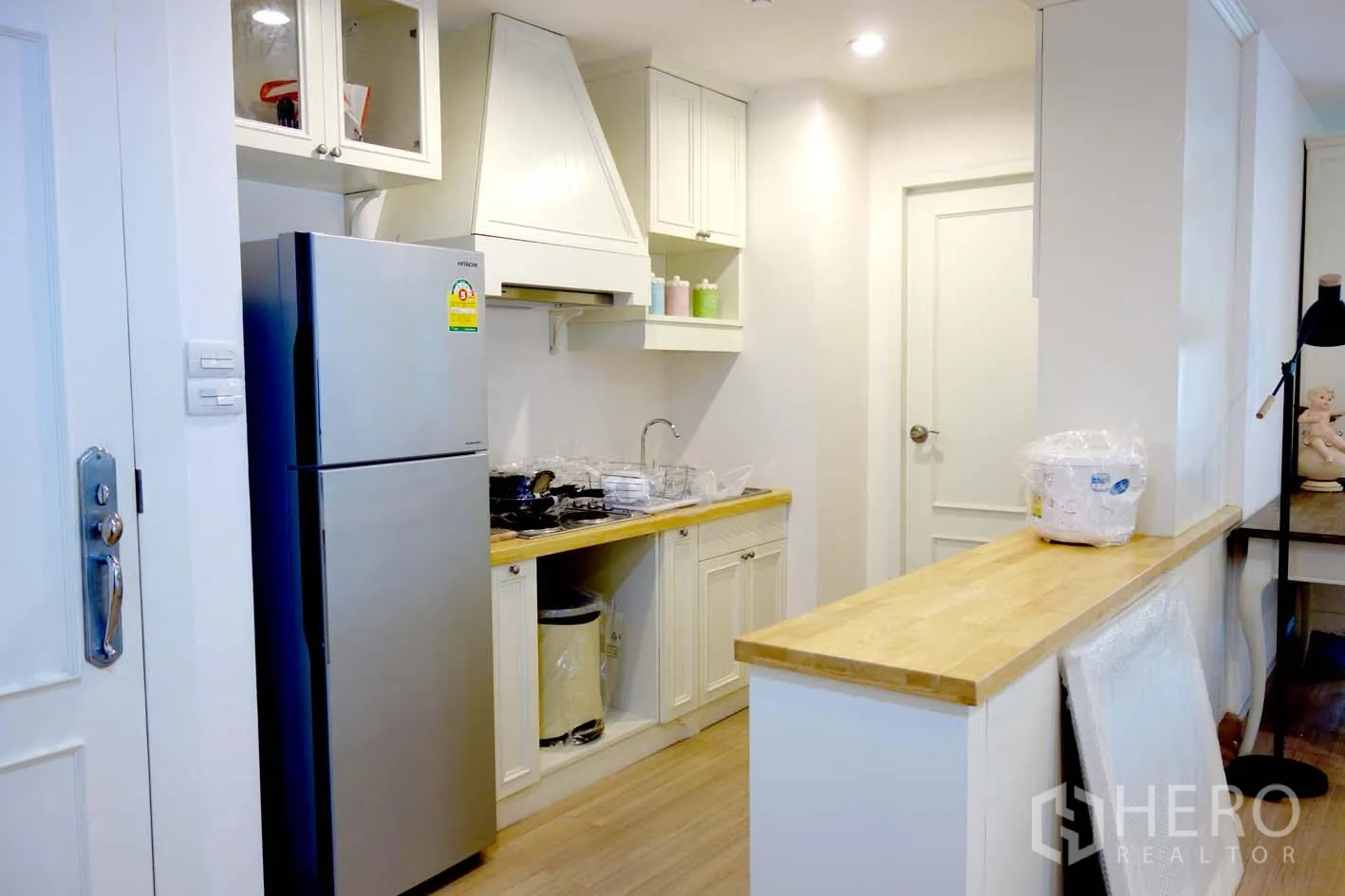 คอนโด ให้เช่าหรือขายในWatthana, Bangkok - ครัวคอนโดย่านวัฒนา โทนขาวสว่าง เคาน์เตอร์ไม้ ตู้เย็นสแตนเลส เตาแก๊ส และเคาน์เตอร์บาร์