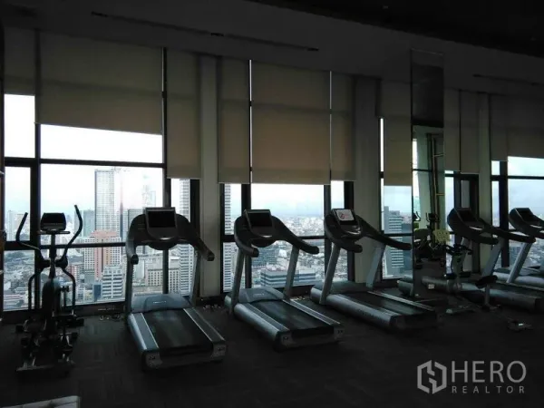 公寓 出租在Bang Rak, Bangkok - 健身房内多台跑步机，落地窗俯瞰城市