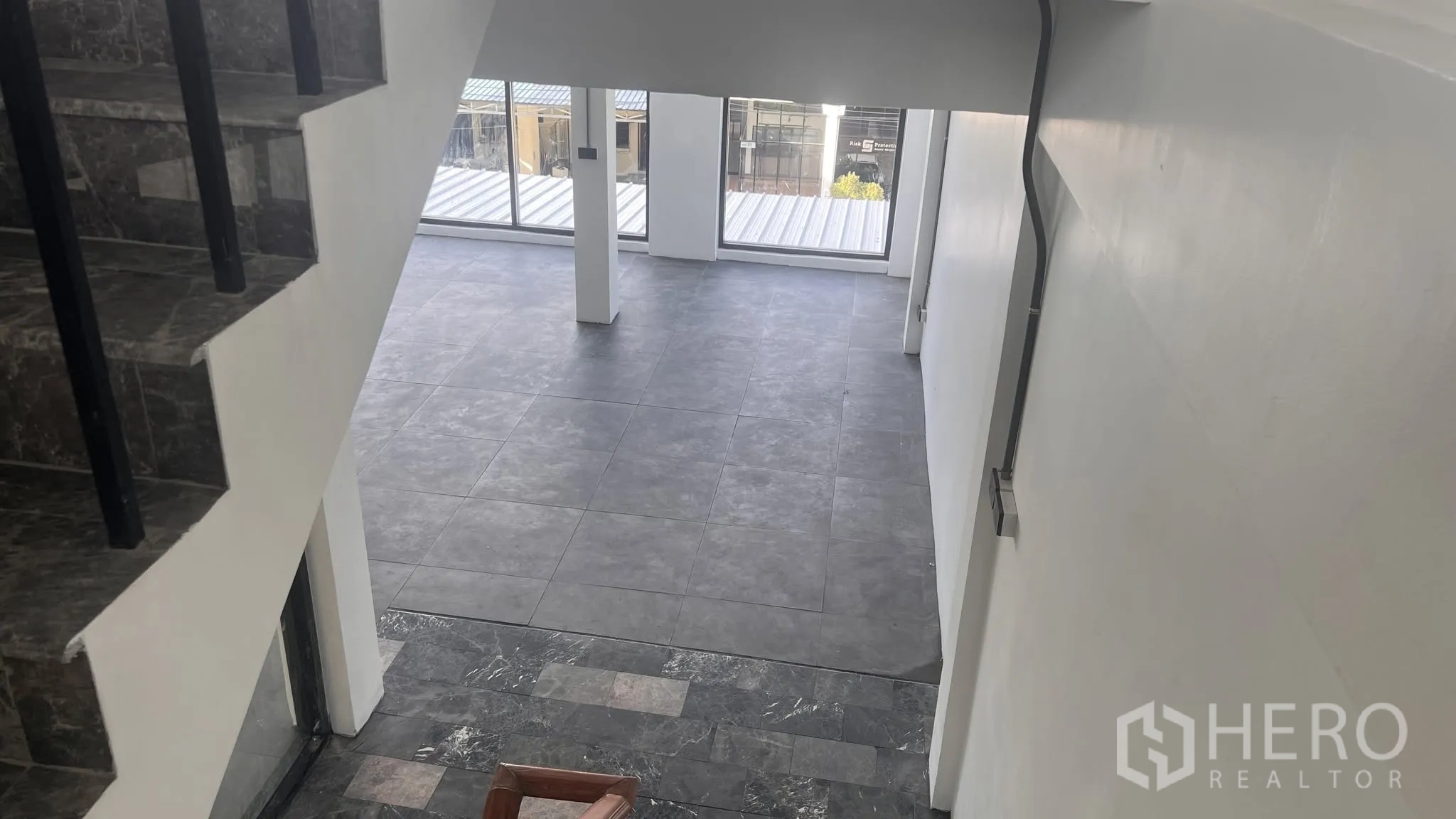 โฮมออฟฟิศ for rent or sale in Phra Khanong, Bangkok - มุมมองจากบันไดสู่ชั้นเปิดโล่งปูกระเบื้องและมีหน้าต่างบานใหญ่.