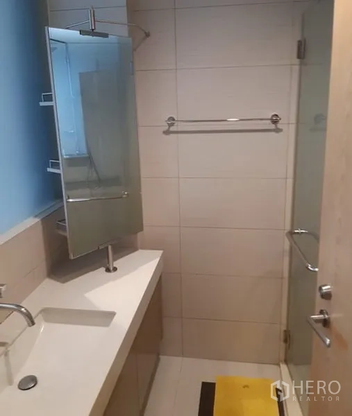 公寓 出租在Khlong Toei, Bangkok - 瓷砖卫浴，长台面与盥洗盆，墙镜，玻璃淋浴间和金属配件。