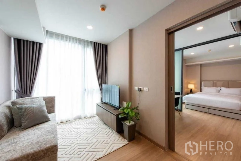 Condominium for rent in Huai Khwang, Bangkok - Cozy lounge with sofa, TV stand and access to the master bedroom.