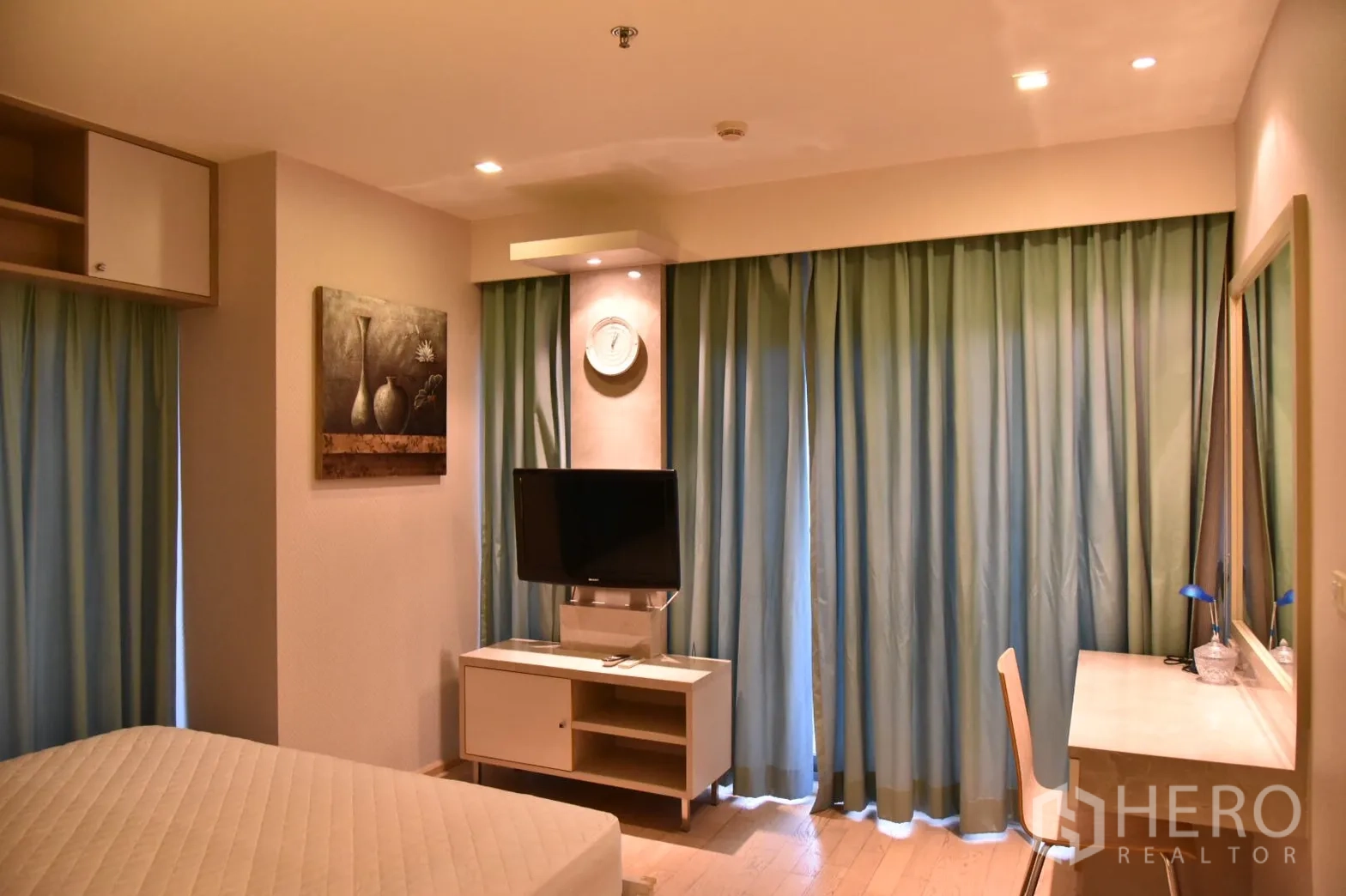 Condominium for rent or sale in Khlong Toei, Bangkok - Bedroom with TV console, long work desk and floor-to-ceiling curtains.