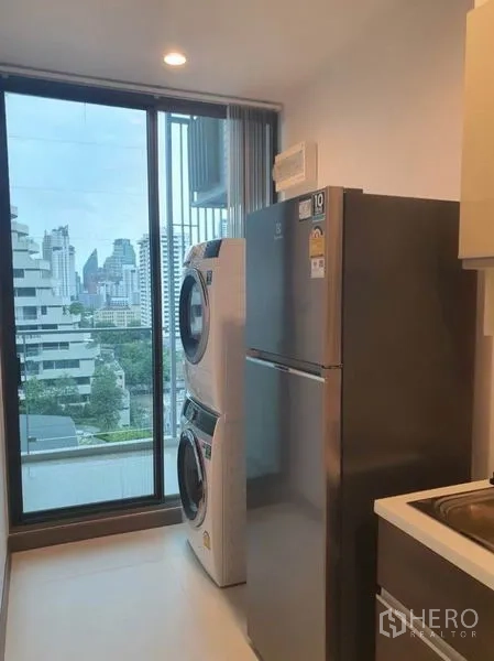 คอนโด ให้เช่าในWatthana, Bangkok - ระเบียงซักล้างพร้อมเครื่องซักผ้าอบผ้าแบบตั้งซ้อน ตู้เย็นสูง และประตูกระจกมองวิวสกายไลน์