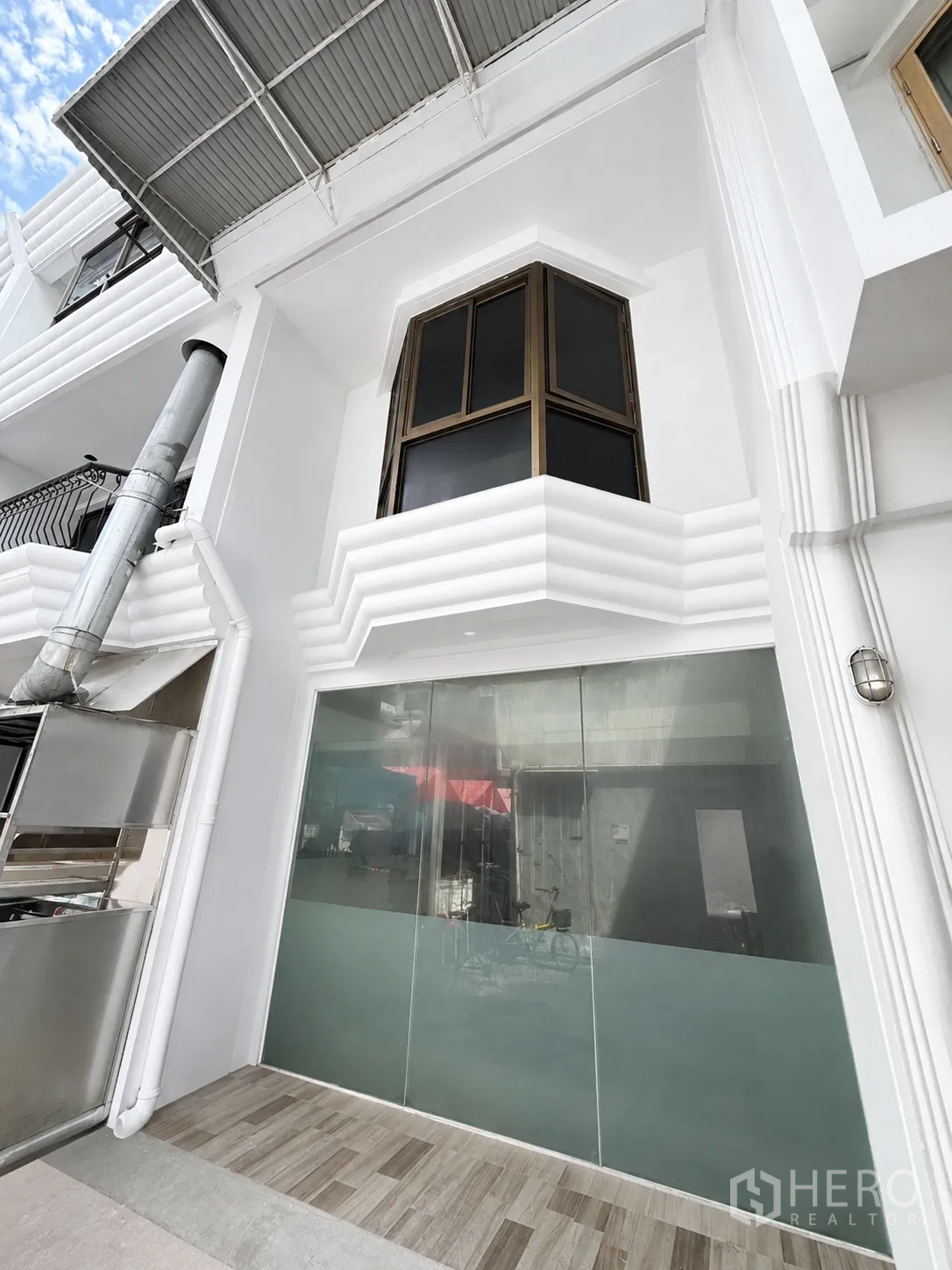 Retail Space for rent in Pathum Wan, Bangkok - White building facade featuring a large frosted glass storefront, covered awning, and upper bay window.