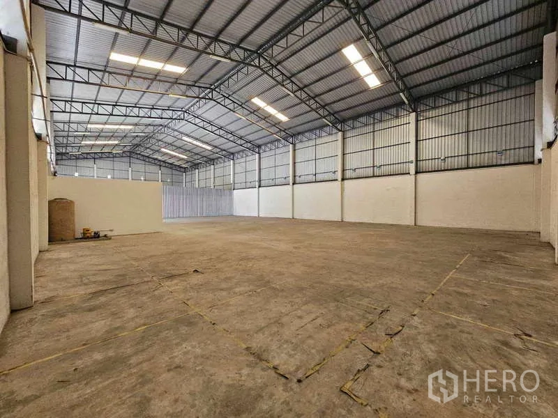 Warehouse for rent in Bang Bua Thong, Nonthaburi - Expansive warehouse bay with ventilated metal walls, high ceiling, and smooth concrete floor.