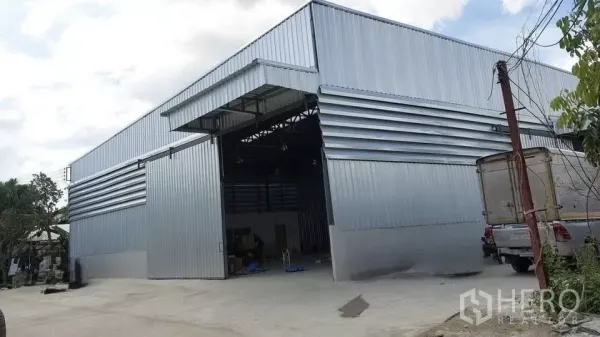 Warehouse for rent in Khlong Sam Wa, Bangkok - Modern metal-clad warehouse exterior with wide sliding door and a spacious concrete yard for truck access.