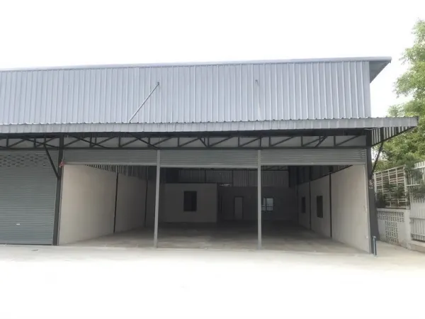 คลังสินค้า ให้เช่าในPathum Thani - ด้านหน้าโกดังผนังเมทัลชีท พร้อมลานโหลดมีหลังคาและประตูม้วนกว้าง ในคูคต ลำลูกกา