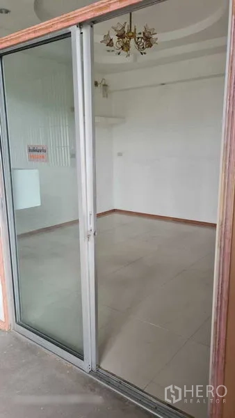 Warehouse for rent in Bang Kapi, Bangkok - Close-up of the sliding glass door to the office, revealing a bright tiled room.