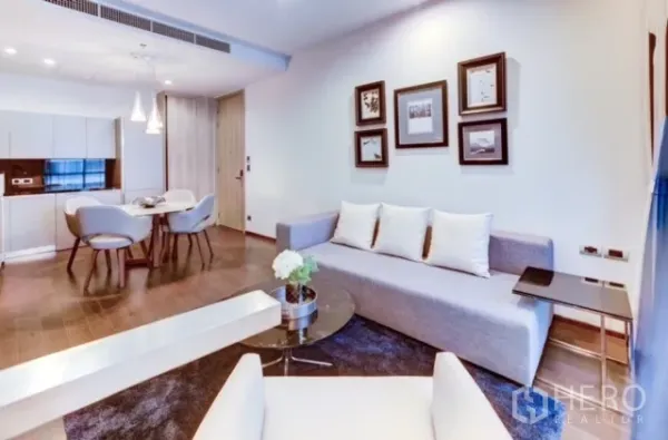 คอนโด ให้เช่าหรือขายในWatthana, Bangkok - ห้องนั่งเล่นแบบเปิดโล่ง โซฟาสีเทา กรอบรูป โคมไฟแขวน พื้นไม้ และครัวบิลต์อิน