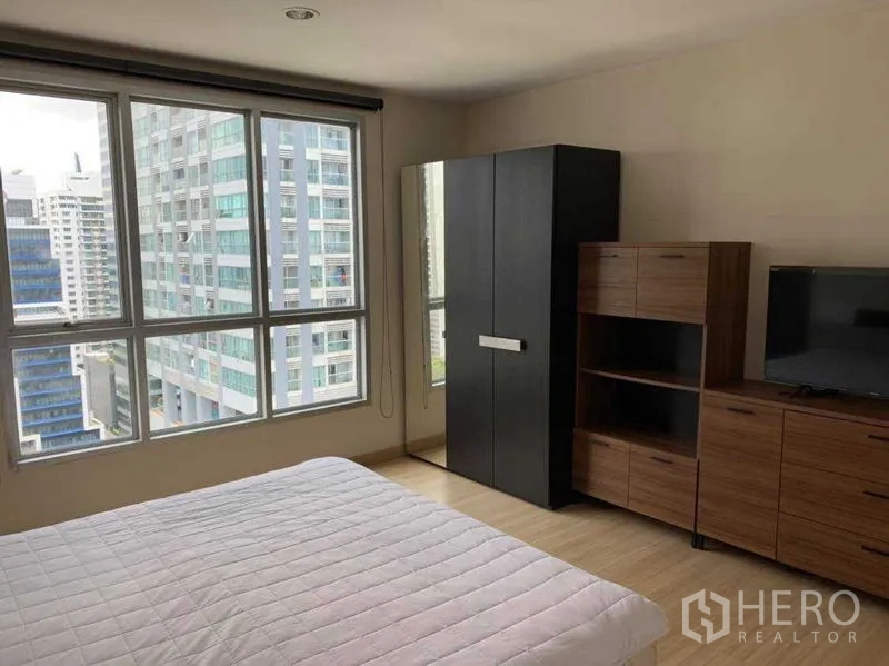 公寓 出租在Bang Rak, Bangkok - 卧室配城市景观窗、衣柜、置物柜与电视柜。