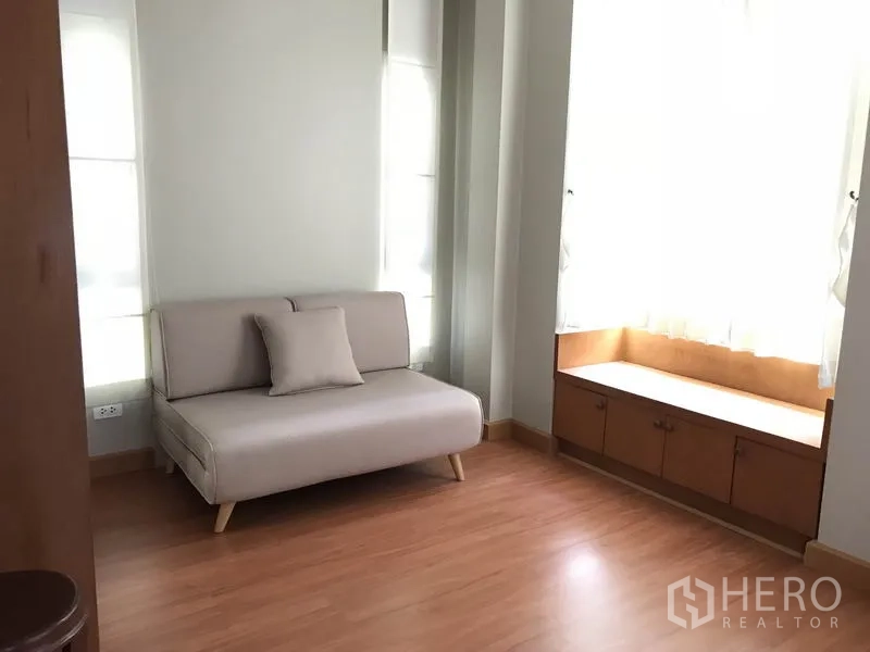 บ้าน ให้เช่าในKhlong Toei, Bangkok - มุมนั่งเล่นอบอุ่น โซฟาโทนอ่อน ม้านั่งริมหน้าต่าง และพื้นไม้