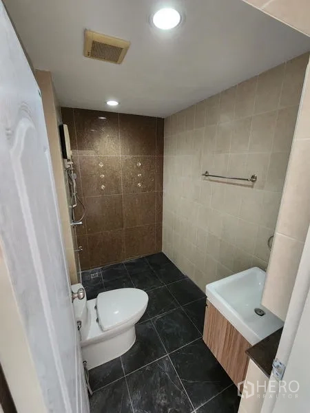 Townhouse for rent in Wang Thonglang, Bangkok - Second bathroom with tiled shower area, toilet and compact vanity.