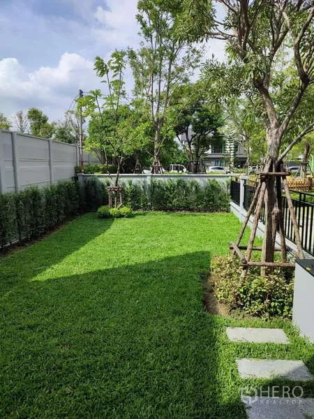 Detached House for rent in Bang Phli, Samut Prakan - Private backyard with green lawn, stepping stones, trees and boundary wall.