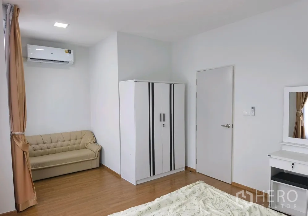 Townhouse for rent in Bang Phli, Samut Prakan - Spacious bedroom with sofa, wardrobe, air conditioner and dressing table.