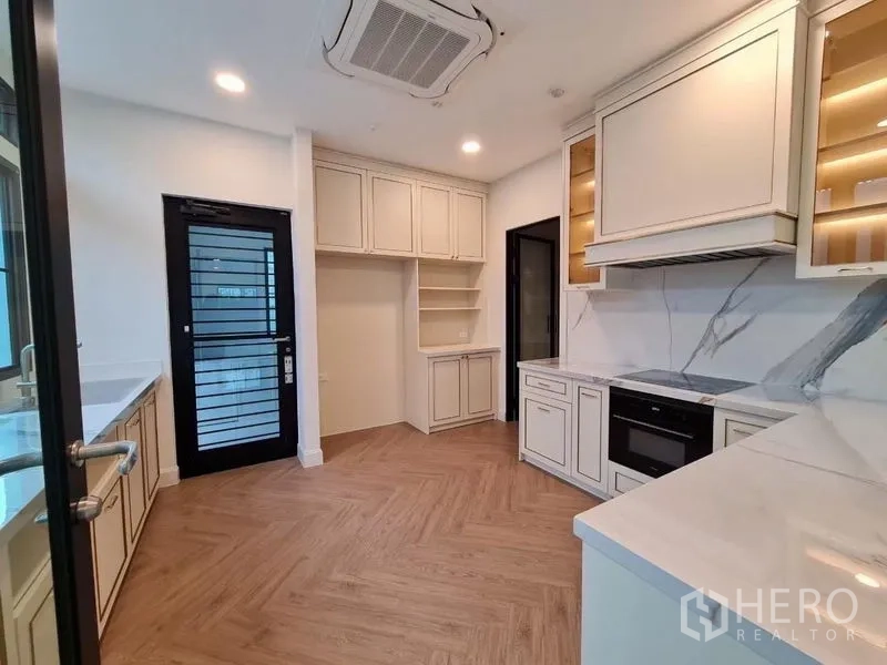 Detached House for rent or sale in Saphan Sung, Bangkok - Modern kitchen with shaker cabinets, marble backsplash and herringbone wood floor.